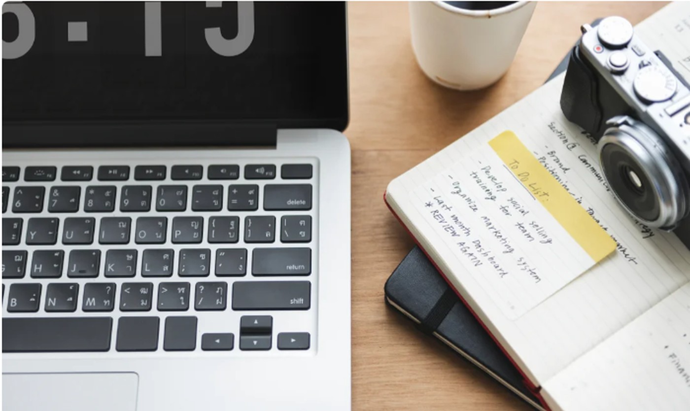 Laptop, camera and notebook on a creative workspace